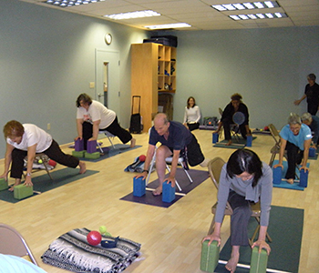 Jenny Otto teaches lunge pose to chair yoga class